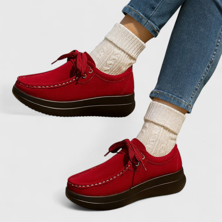 Red lace-up orthopedic shoe with suede upper and thick dark sole.