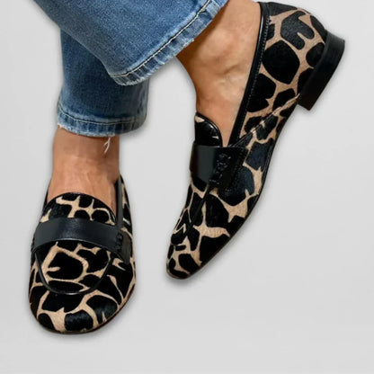 Leopard moccasin flats with black strap across vamp, worn with blue jeans