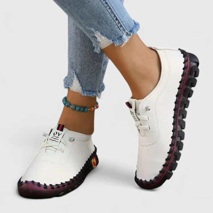 White leather lace-up casual shoes with dark tread sole and side emblem