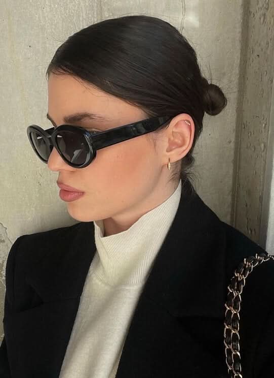 Black cat-eye sunglasses on model, dark lenses and curved temples