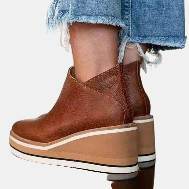 Brown wedge ankle boots with side elastic and layered sole with white and dark stripes.