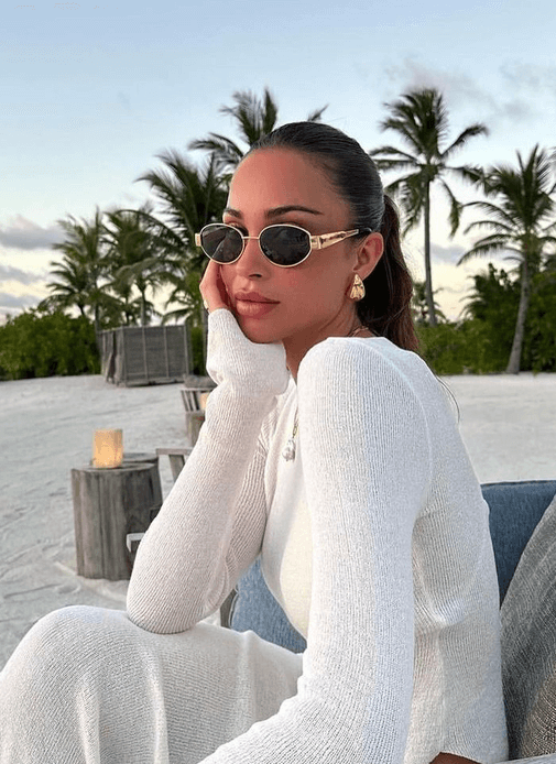 Round sunglasses on face with dark lenses and thin gold frame