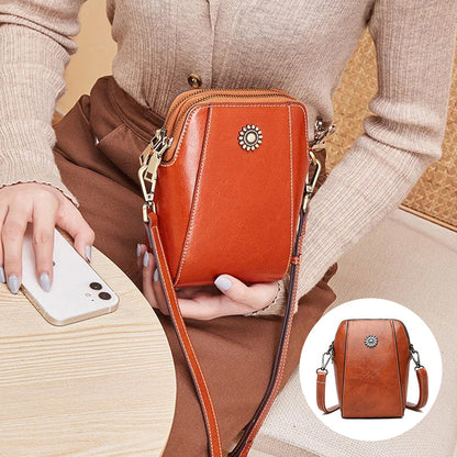 Orange mini crossbody handbag with zipper and sunburst emblem