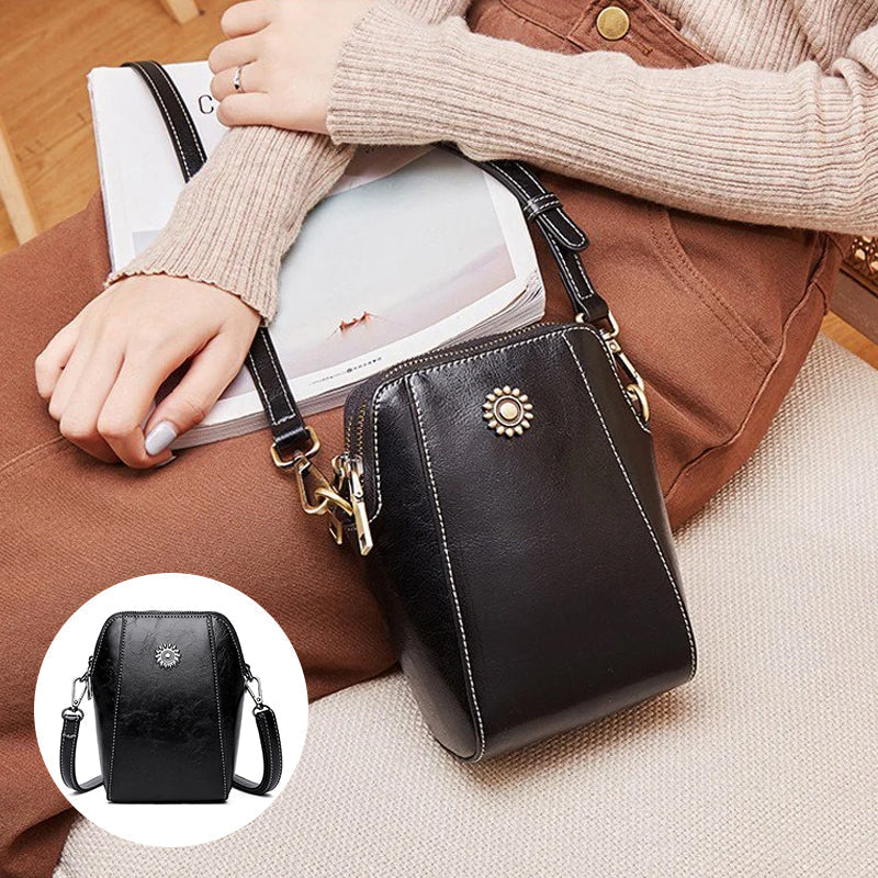 Black compact mini handbag with crossbody strap and zipper closure; front sunburst emblem.