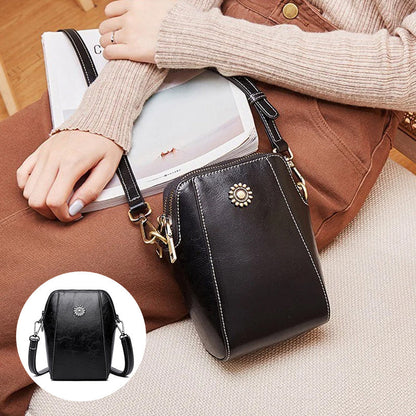 Black compact mini handbag with crossbody strap and zipper closure; front sunburst emblem.