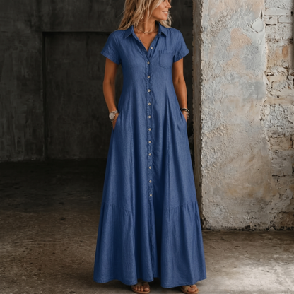 Long denim dress in dark blue with short sleeves, button front, and gathered skirt