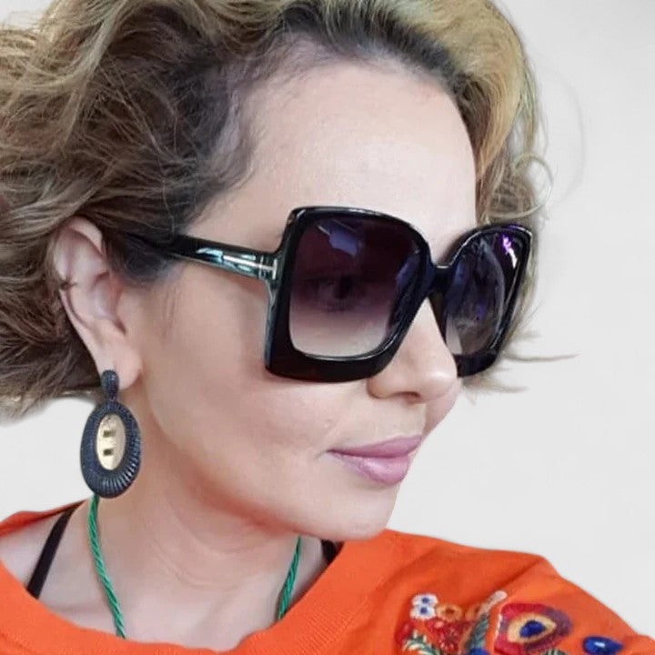 Bold square black sunglasses with dark tinted lenses and gold-toned side accents