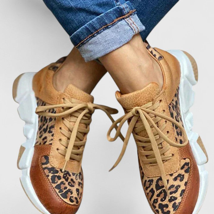 Leopard-print lace-up sneakers on feet, tan laces and white chunky platform sole