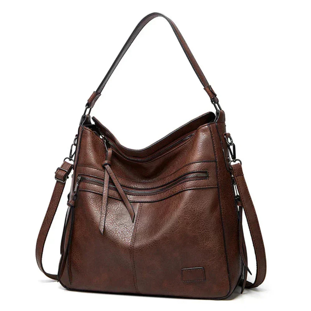 Dark brown hobo shoulder bag with front zip pockets, tassel detail, and side straps