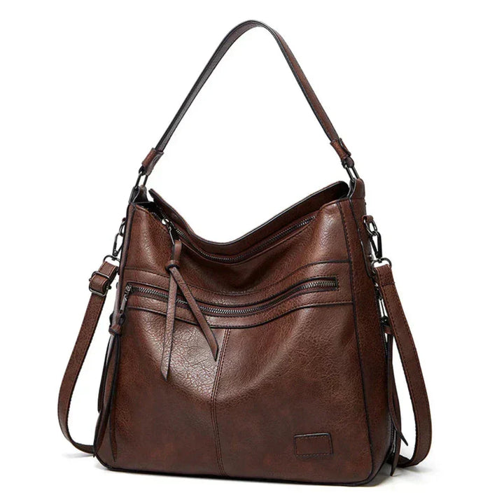 Dark brown hobo shoulder bag with front zip pockets, tassel detail, and side straps