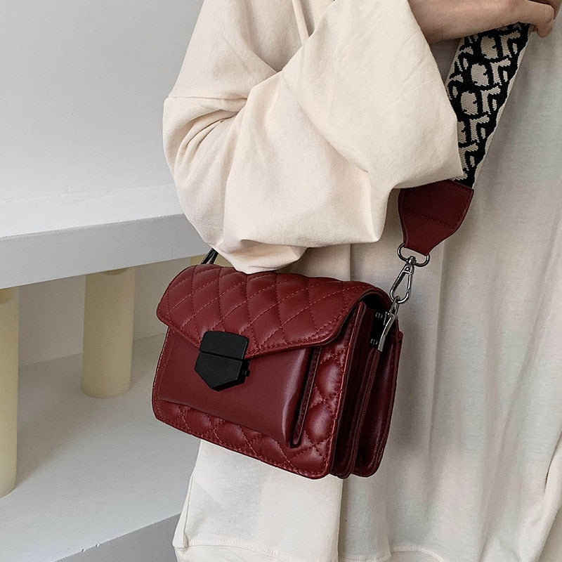 Red shoulder handbag with flap, buckle clasp, and adjustable crossbody strap