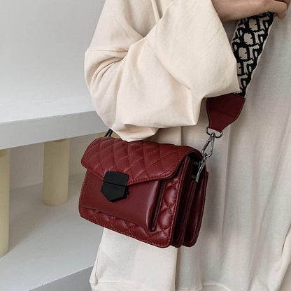 Red shoulder handbag with flap, buckle clasp, and adjustable crossbody strap