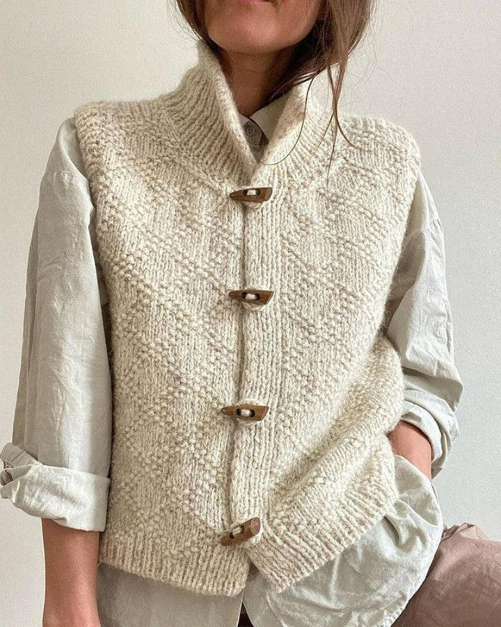 Cream sleeveless knit cardigan with front toggle buttons and ribbed hem