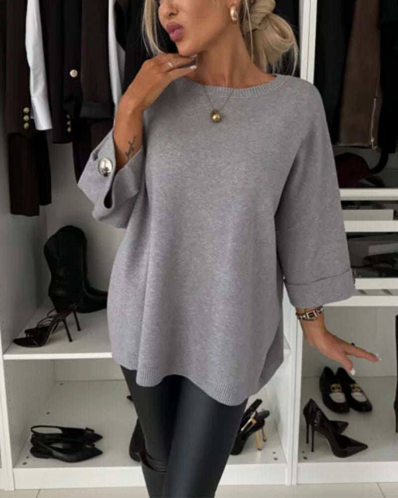 Grey knit pullover with round neckline and subtle button detail on the cuff.