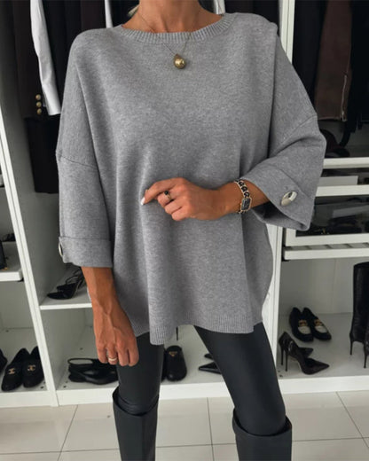 Grey pullover sweater with buttoned cuff detail and round neckline.