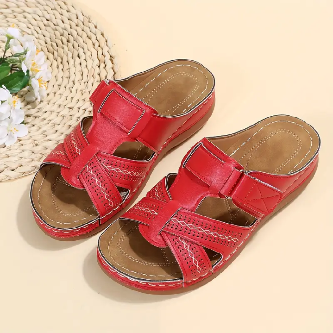 Red ergonomic sandals with two wide straps, perforated cutouts, and tan lining