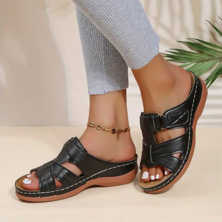 Black ergonomic sandals with double adjustable straps, perforated upper, and tan outsole