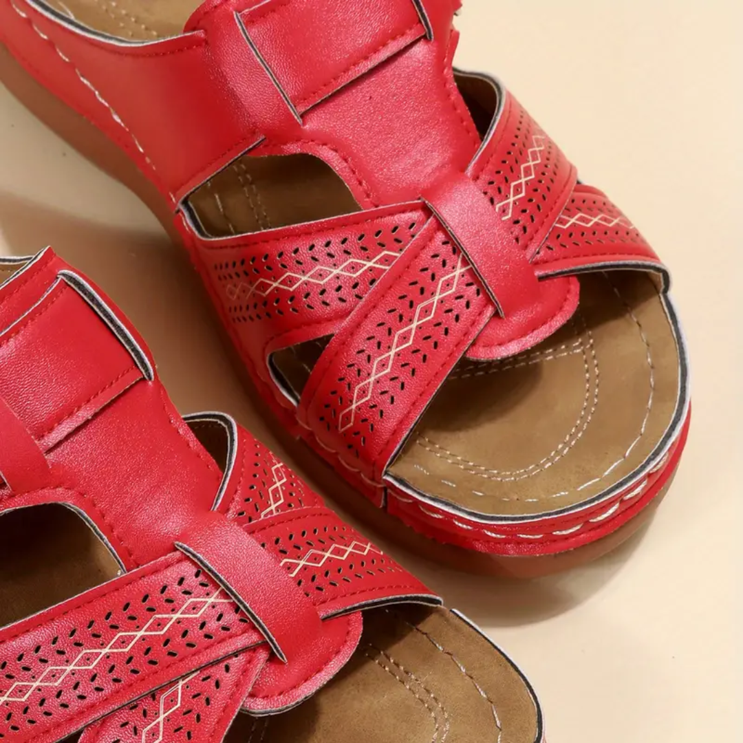 Red ergonomic sandals with perforated panels, two straps, and tan footbed stitching
