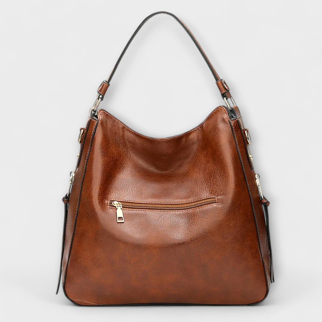 Brown hobo handbag with curved top, front zip pocket, and two shoulder straps