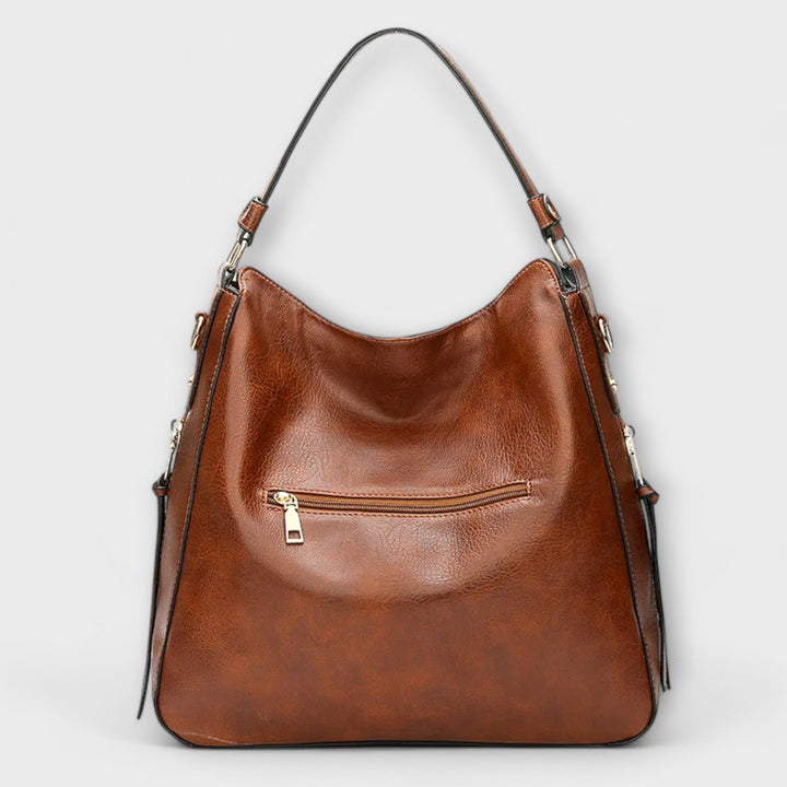 Brown hobo handbag with curved top, front zip pocket, and two shoulder straps