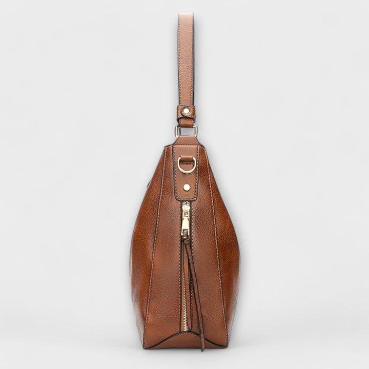 Brown hobo handbag side view with adjustable shoulder strap and gold-tone hardware
