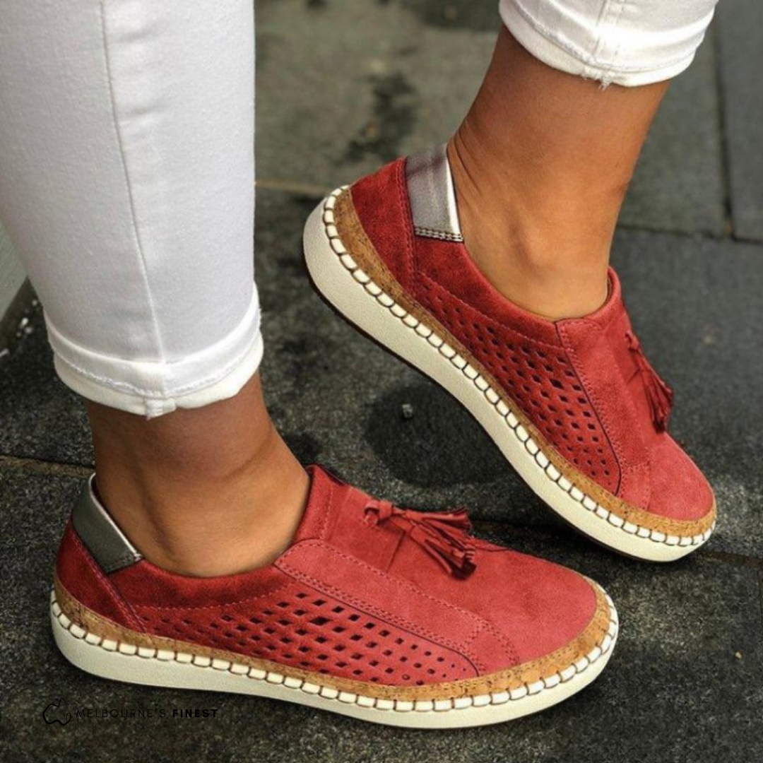 Red orthopedic slip-on shoes with tassel detail, perforated upper, and cream sole