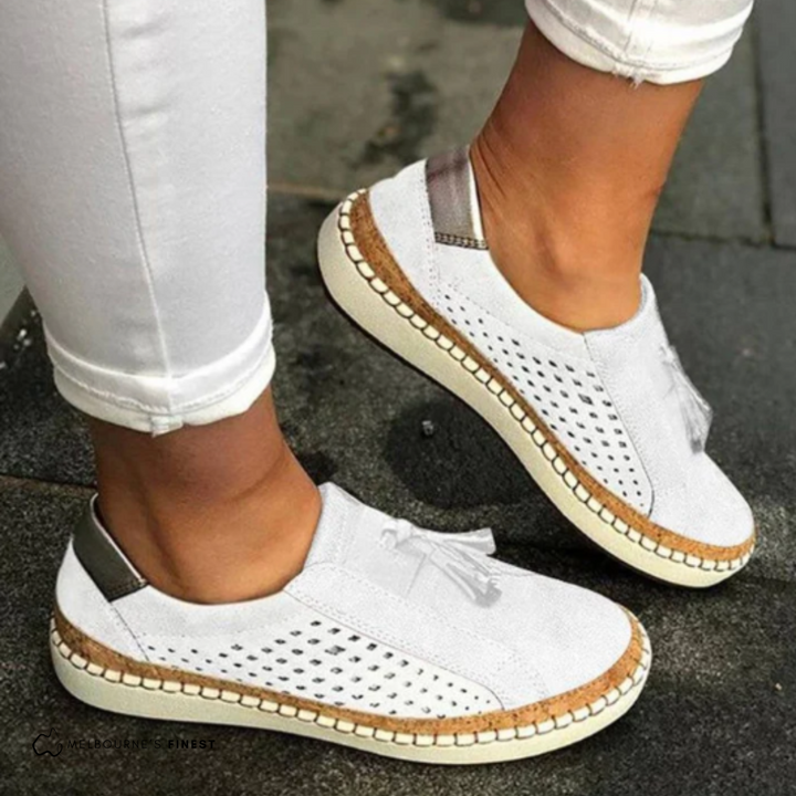 White orthopedic slip-on shoes with tassel detail, perforated upper, and cream sole