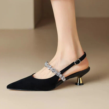 Black pointed-toe pumps with rhinestone strap and gold-tone heel
