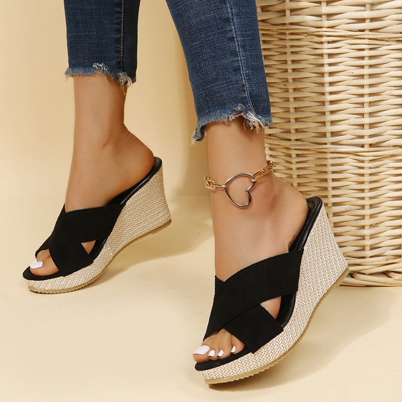 Black relaxed wedge sandals with ankle strap buckle and wide crisscross toe straps.