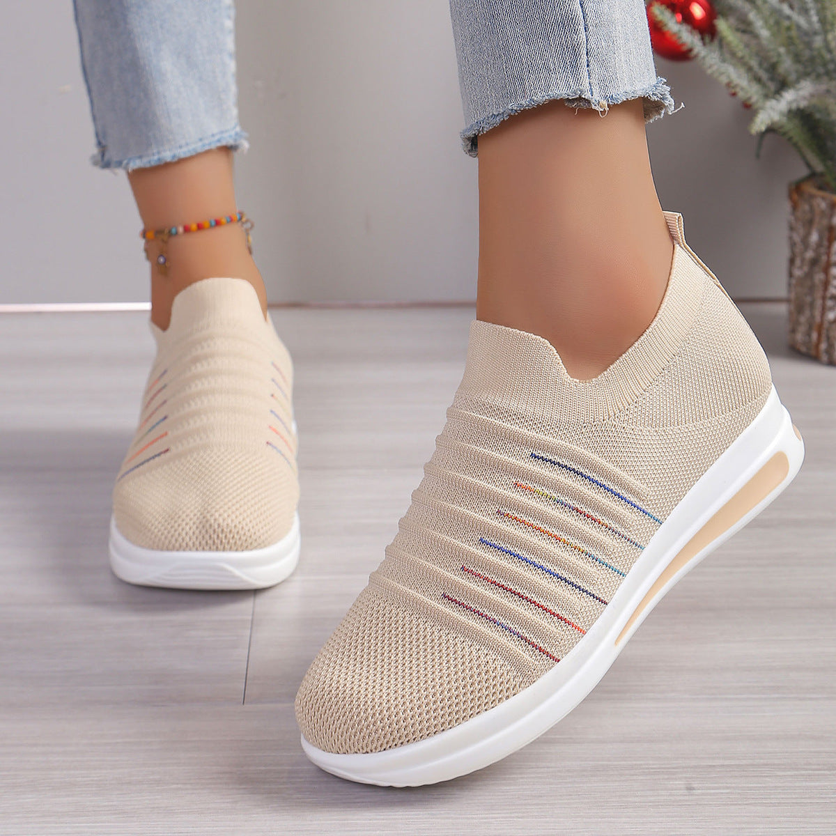 Beige knit slip-on sneakers with multicolor stripe detail and cushioned white sole