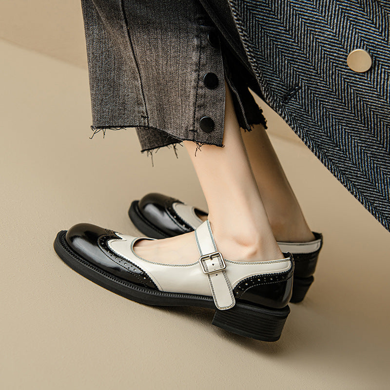 White-and-black Mary Jane shoes with buckle strap and wingtip-style stitching
