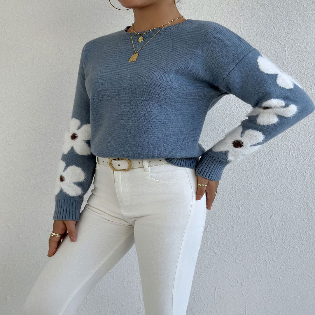 Blue round-neck sweater with white flower patterns on sleeves and ribbed cuffs