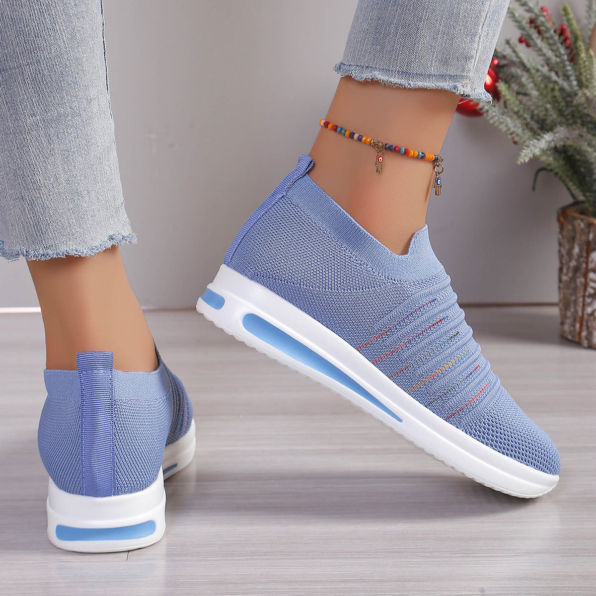 Blue knit slip-on sneakers with multicolor stripe detail, rear and side view, white sole