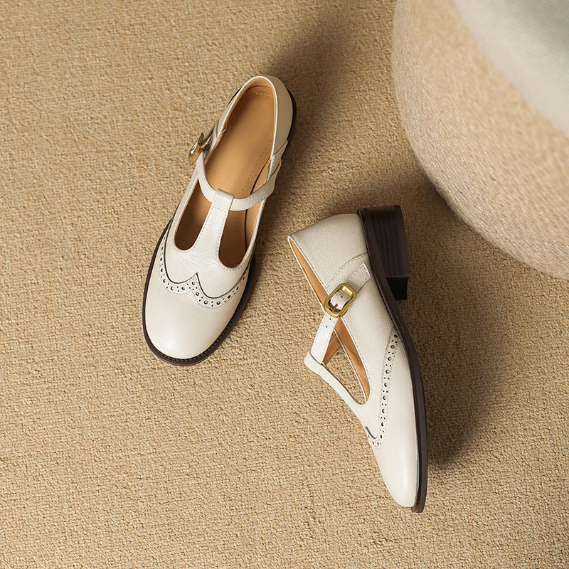 Off-white Mary Jane shoes with ankle strap, gold buckle, and perforated toe