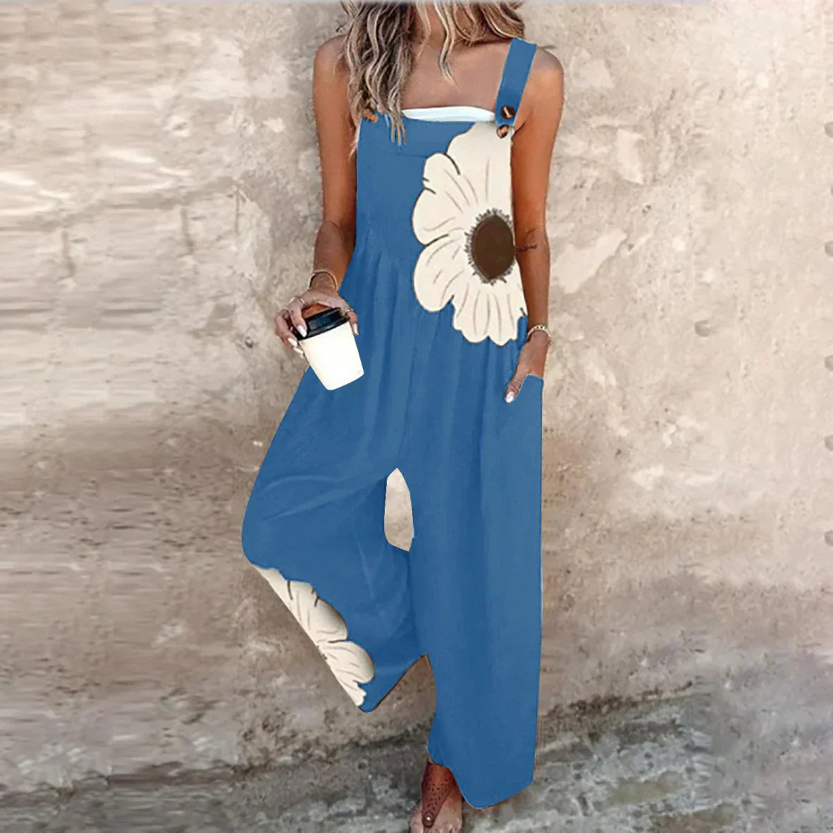 Blue sleeveless printed overalls with white daisy motif and wide-leg loose fit.