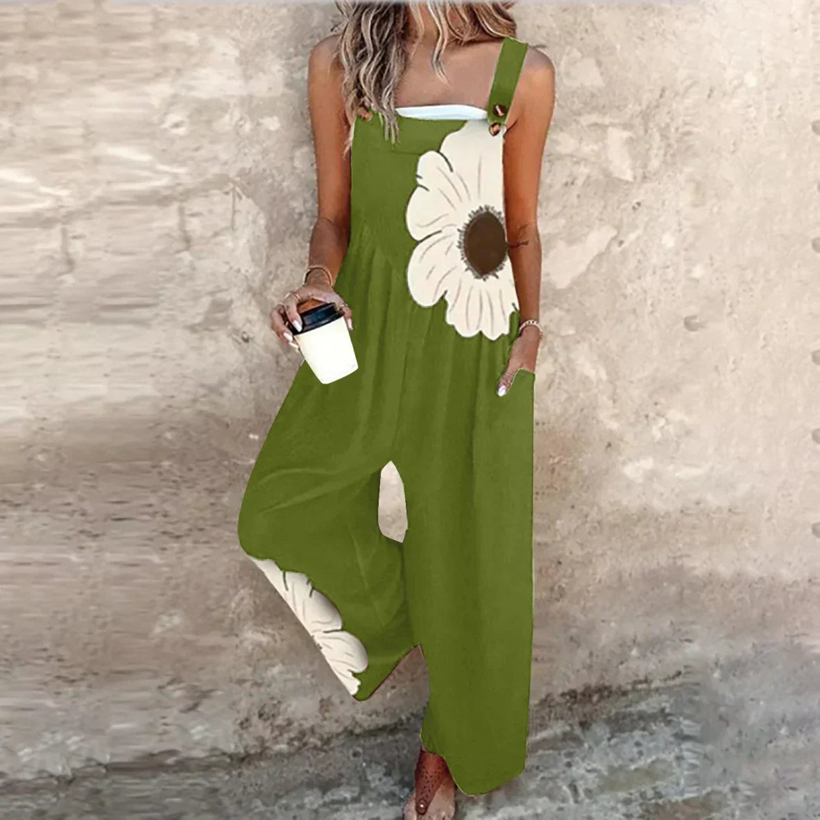 Green sleeveless printed overalls with white daisy motif and wide-leg loose fit.