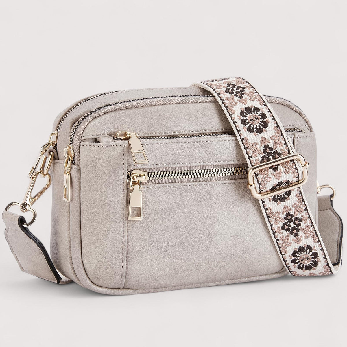Light grey lightweight crossbody bag with top zip, front pocket, and patterned strap.