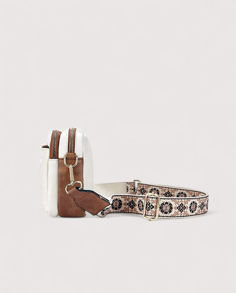 White lightweight crossbody bag with patterned strap and adjustable buckle hardware.