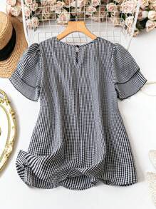 Black-and-white checkered short-sleeve blouse with gathered shoulders and peplum hem