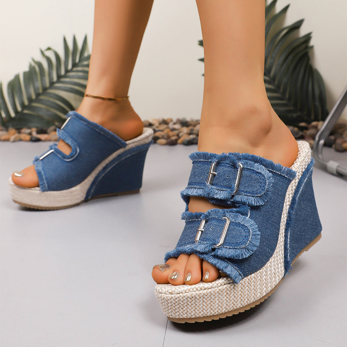 Blue denim wedge sandals with two buckle straps and open toe, angled front view
