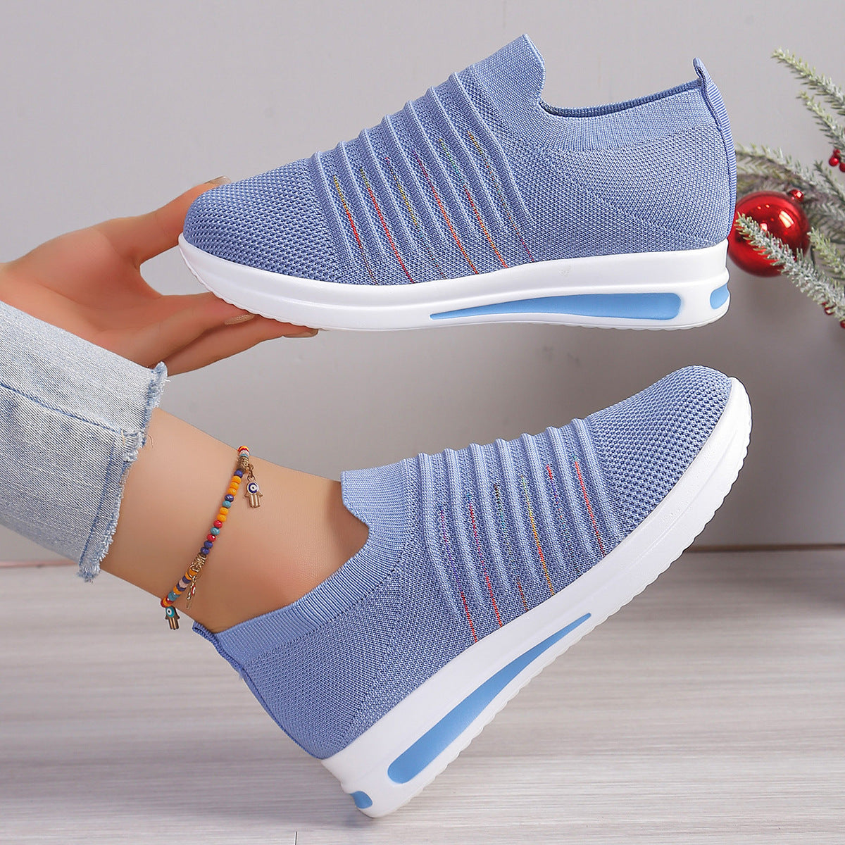Blue knit slip-on sneakers shown from side, multicolor stripe detail, white sole