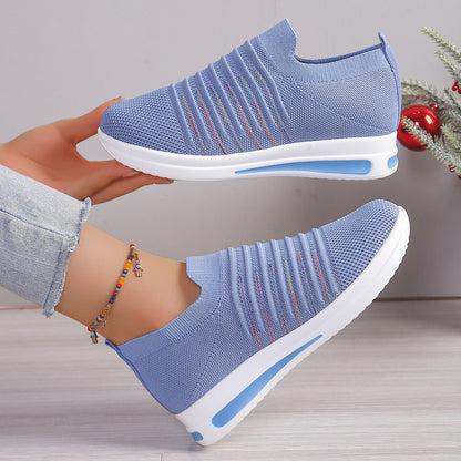 Blue knit slip-on sneakers shown from side, multicolor stripe detail, white sole