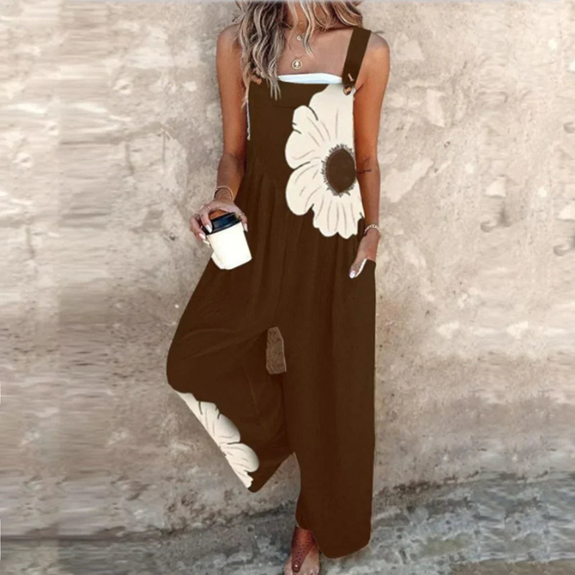 Brown sleeveless printed overalls with white daisy motif and wide-leg loose fit.