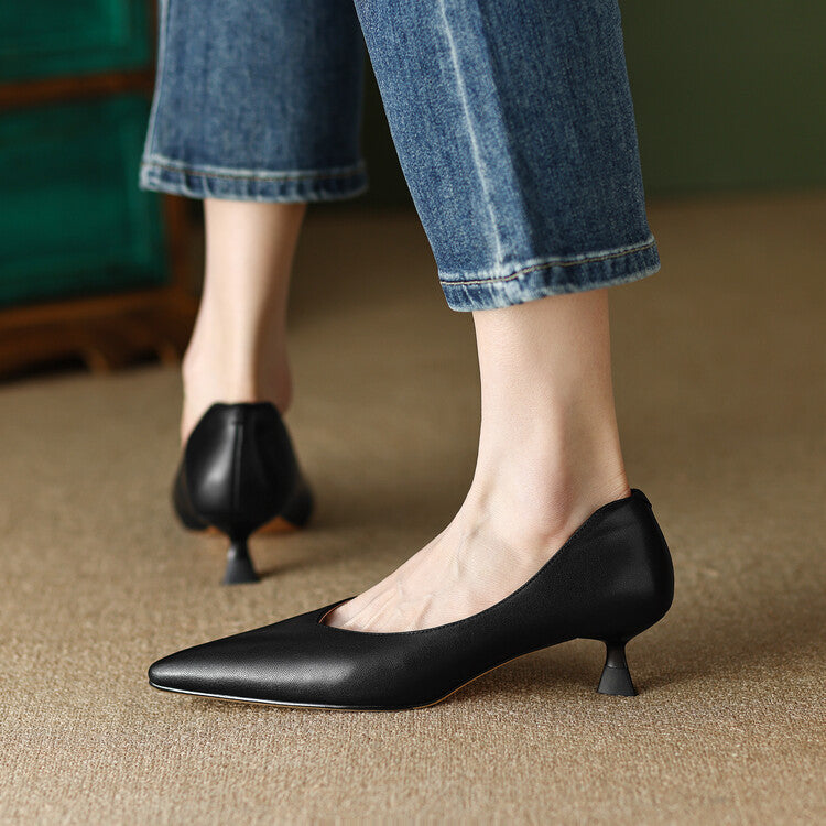 Black pointed-toe pumps with low block heel, side view on foot