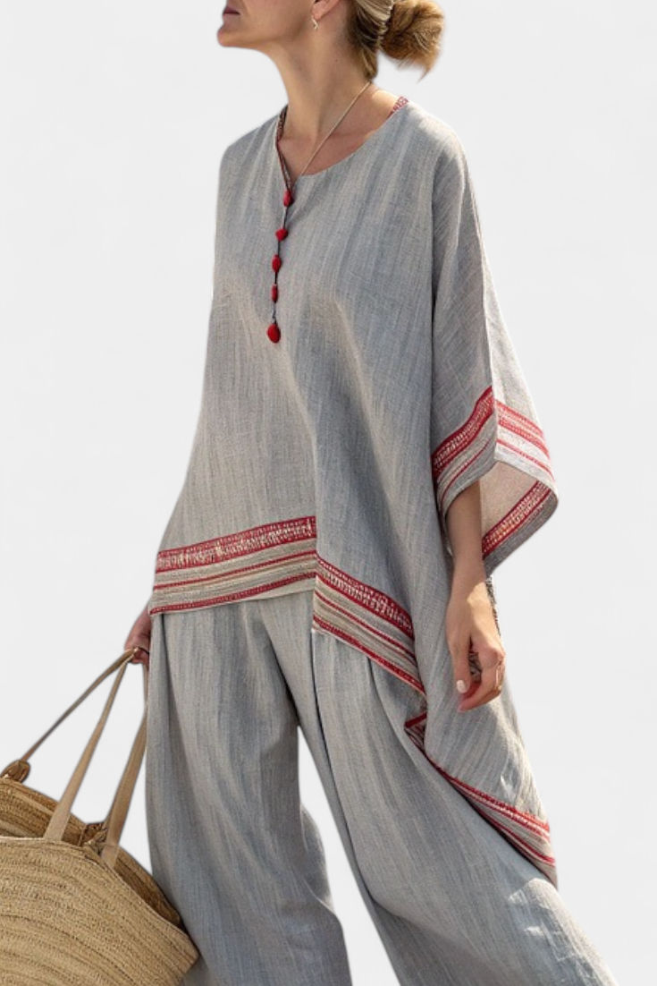 Asymmetric gray blouse with red striped hem and red tassel neckline detail
