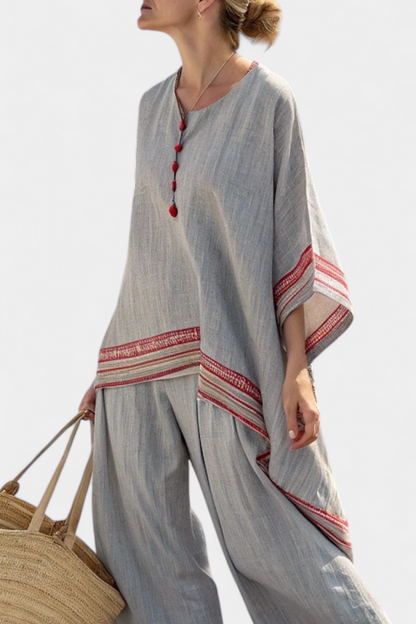Asymmetric gray blouse with red striped hem and red tassel neckline detail