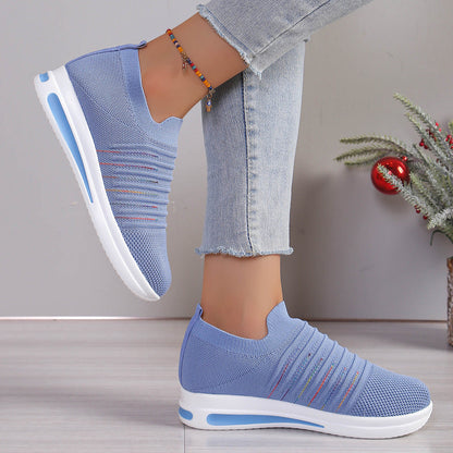 Blue knit slip-on sneakers with multicolor stripe detail and white sole, angled view