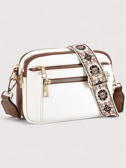 White lightweight crossbody bag with top zip, front pocket, and patterned strap.