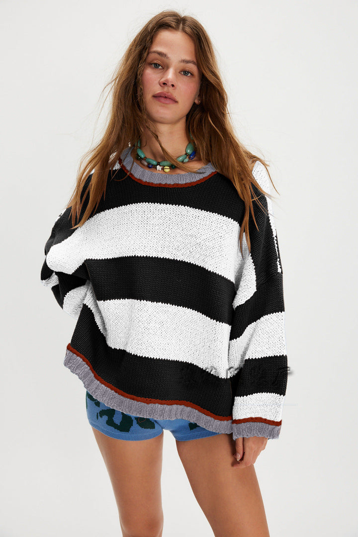 Striped crew neck sweater in black and white stripes with ribbed cuffs and orange hem trim.