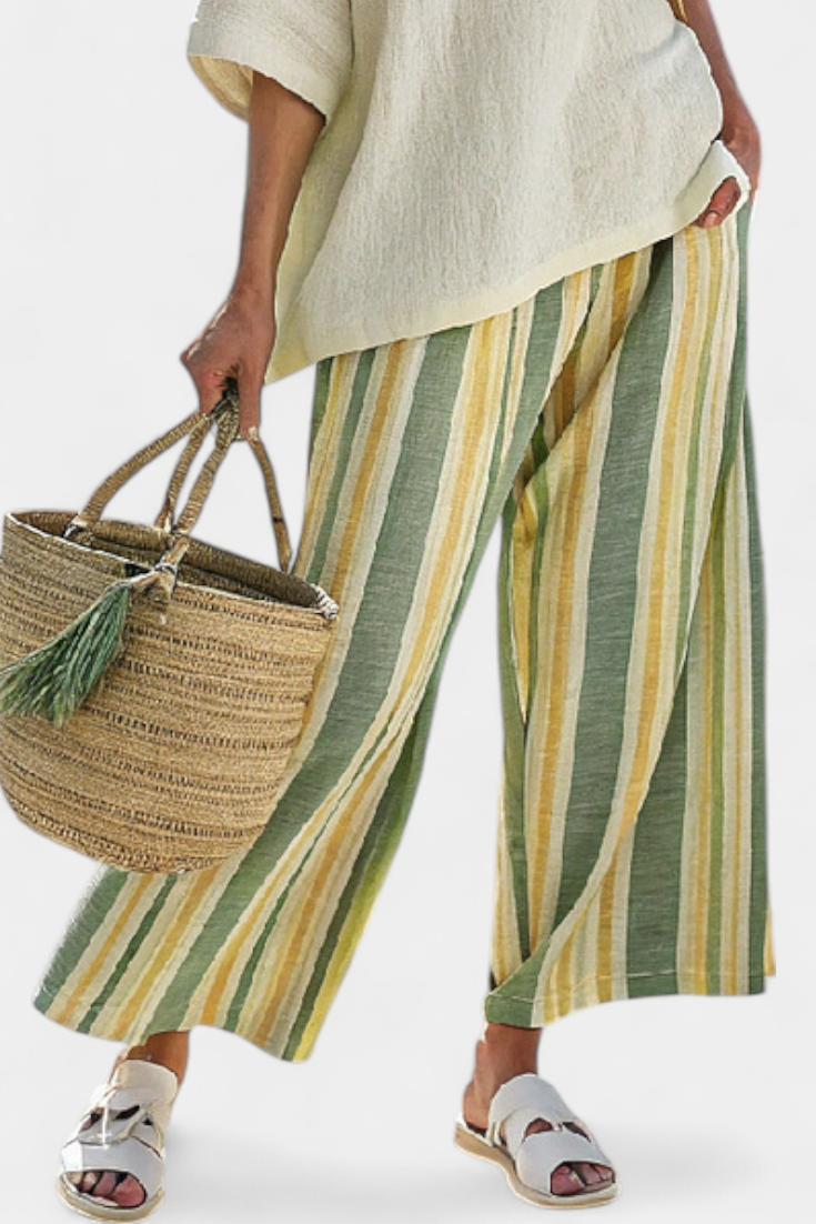 Beige linen top hem over green-and-yellow striped wide-leg trousers, close-up